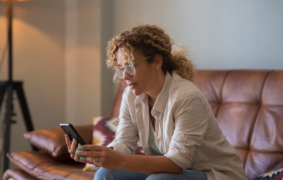 woman sitting on sofa using her mobile phone