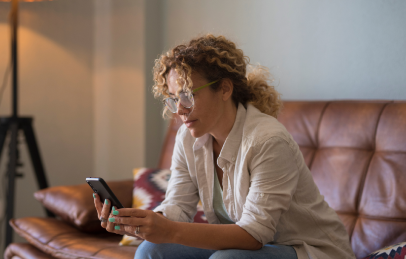 woman sitting on sofa using her mobile phone
