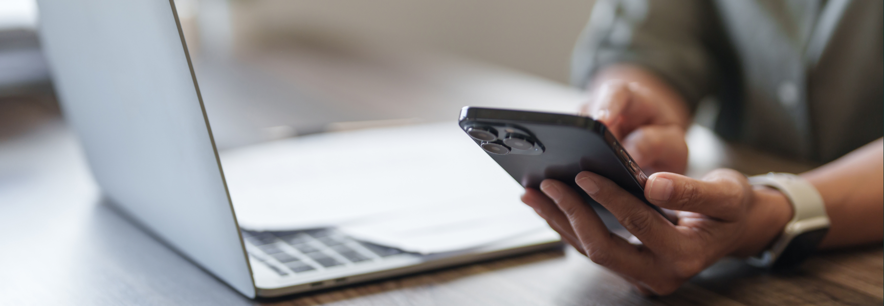 Person holding a mobile phone while laptop is open