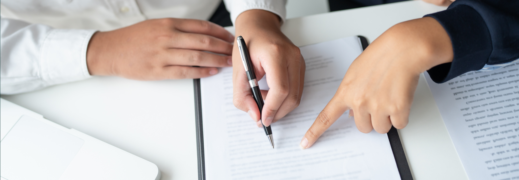 Two people's hands working on a written document