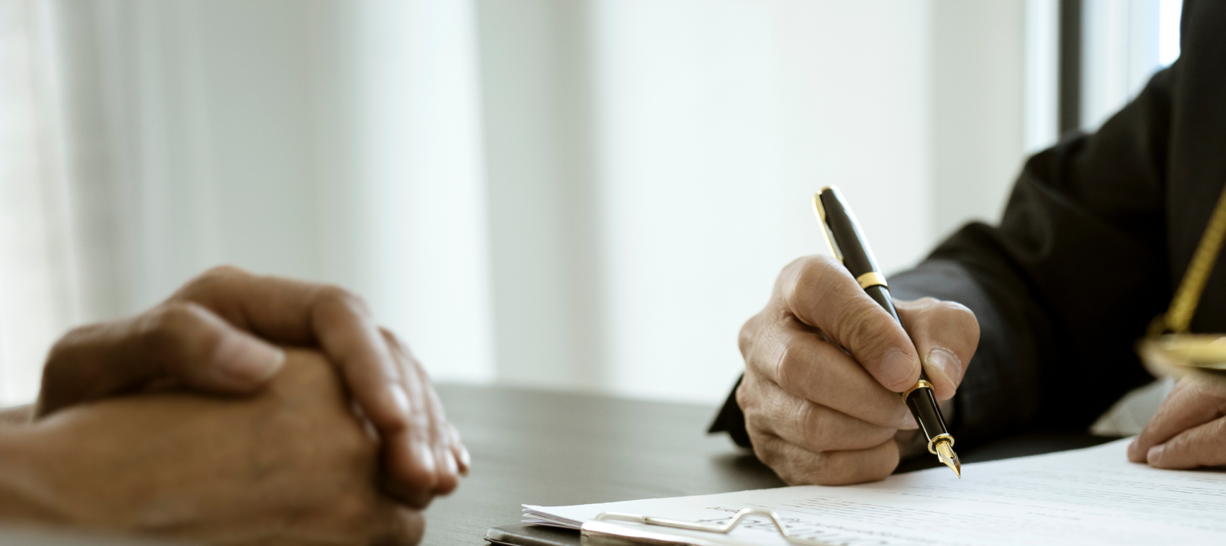 A lawyer's hand writing on a clipboard document